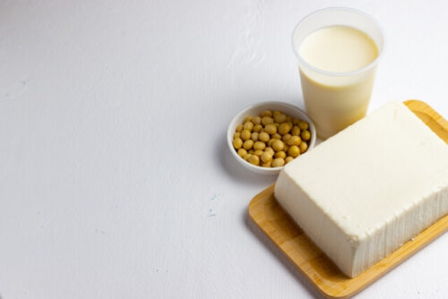 グラスに入った豆乳、白い器に入った大豆、木のトレイにのった豆腐の写真